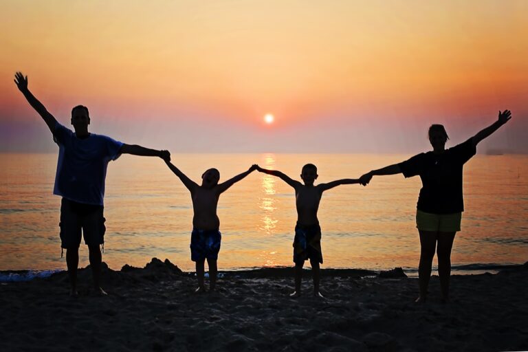 Silhouette of a happy family of four by the beach facing sunset