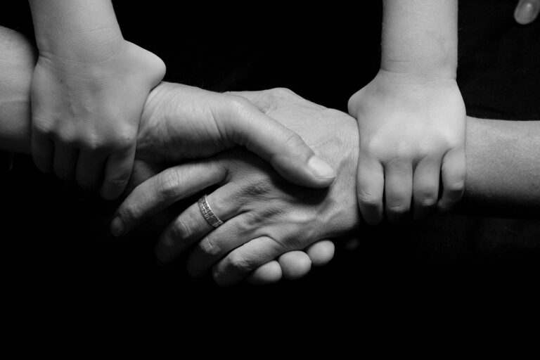 A firm handshake between a man's hand and a woman's hand with both hands held together by a child's pair of hands