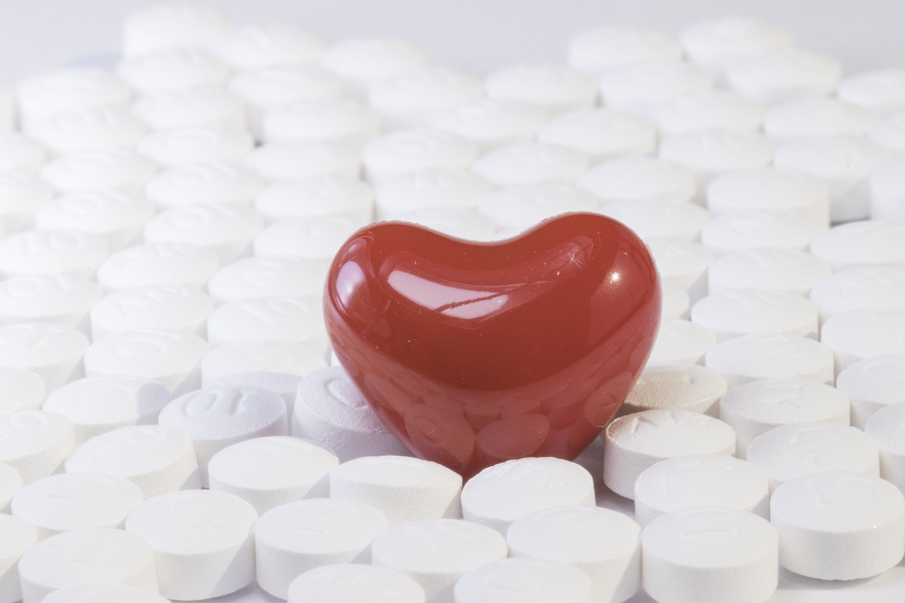 A red heart pill in the middle of white pills to depict healing