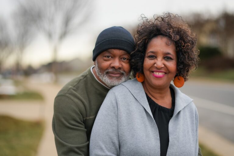 Loving smiling couple with man embracing woman from behind